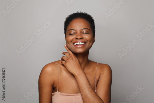 Cute African American female model with healthy fresh clear dark skin posing on white background. Skin care, cosmetology and beauty treatment