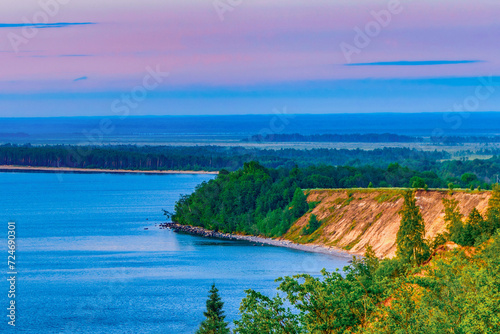 Seascape - the shore of Lake Onega in selective focus against the background of clouds at sunset.Karelian landscape.Concept of traveling around the Russian North.Nature, ecotourism.Forest lake.