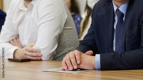 Hands of politician or businessman on the desk next to documents in a transparent file. Official, manager, lawyer or MP. Participating in meeting or negotiations. Photo. Selective focus