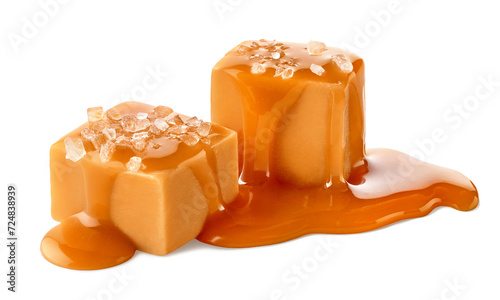 Two salty caramel candy cubes topped with caramel sauce and salt on white background