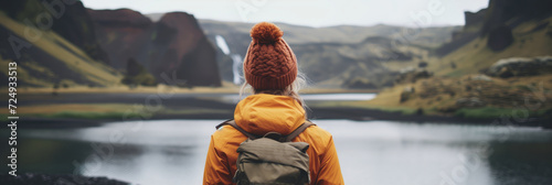 Young female hiker with a backpack admiring scenic view of spectacular Icelandic nature on a sunset. Breathtaking landscape of Iceland. Hiking by foot.