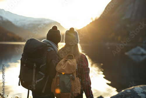 Back view of couple of travelers with a backpacks admiring scenic view of spectacular Norwegian nature. Breathtaking landscape of Norway. Hiking by foot.