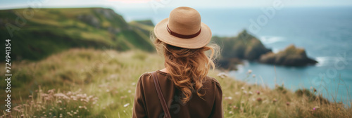 Back view of beautiful young woman admiring scenery while visiting English countryside on sunny summer day. Banner with young female travelling alone.