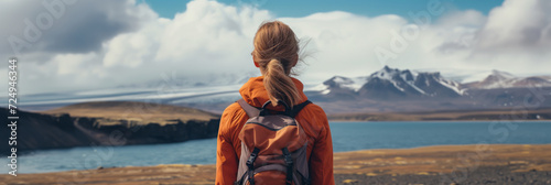 Young female hiker with a backpack admiring scenic view of spectacular Icelandic nature on a sunset. Breathtaking landscape of Iceland. Hiking by foot.