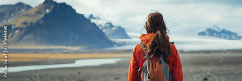 Young female hiker with a backpack admiring scenic view of spectacular Icelandic nature on a sunset. Breathtaking landscape of Iceland. Hiking by foot.
