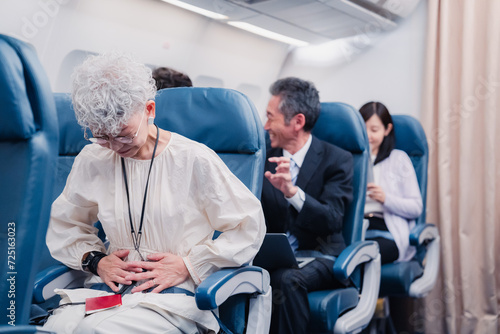 飛行機の機内で体調不良に苦しむ高齢の女性
