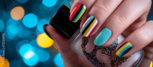 Close-up of a trendy and stylish nail art manicure showcasing colorful nails and a bottle of nail polish.