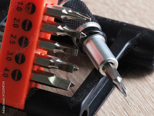 A screwdriver and a set of bits for repairing electronics on a wooden table
