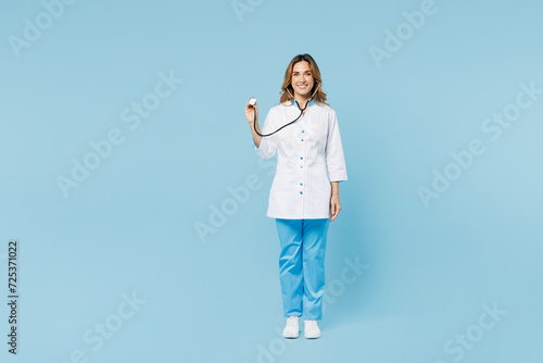 Full body female happy doctor woman wears white medical gown suit work in hospital clinic office hold stethoscope looking camera isolated on plain blue background studio. Health care medicine concept.