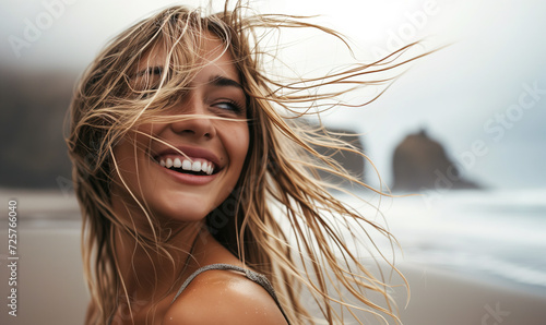beautiful smile of young blonde girl smiling and having fun outdoor on a background of hazy sunshine through a thick mist on a calm sea and blue skies