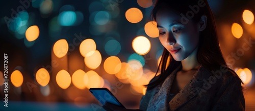 Businesswoman using smartphone at night with bokeh lights for networking and communication idea.