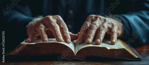 A person's hands engaged in reading a book or being in church, a place of worship for the Christian community, to honor and worship Jesus Christ, the Holy Spirit, and the teachings of the Bible.