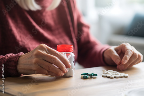 Close-up of the hands of an elderly woman holding a medication bottle, contemplating which pill to take next to continue her therapy.