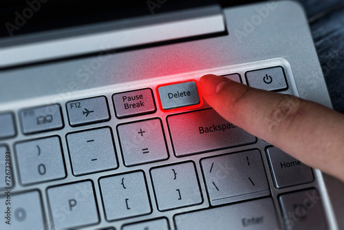 Pressing the delete button on the keyboard with your finger, the effect of red neon lighting. Removing problems, employee, negativity.