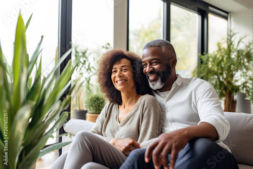 A relaxing and laughing black senior couple, sharing affection and friendship in a cozy home setting.