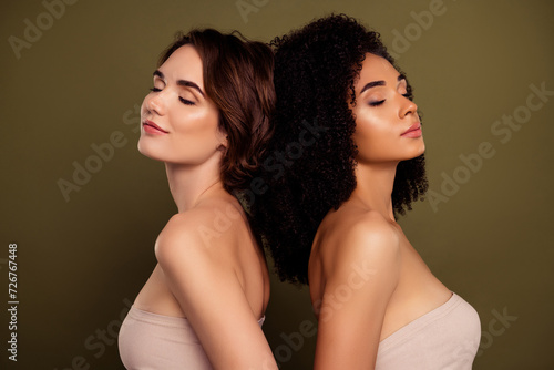 Photo of two girlfriends stand back together closed eyes and dreaming together isolated on khaki color background