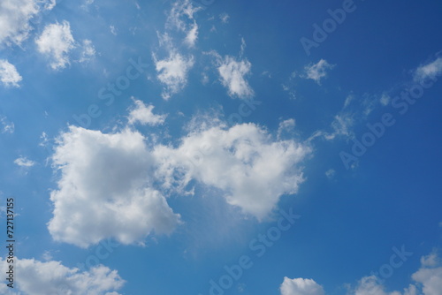 White fluffy clouds in the sky. Blue sky and cloud cover on a sunny summer day. Empty background, copy space
