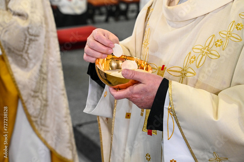 Catholic priest gives holy communion to believer in cathedral. Midnight Holy Mass on Christmas Eve. Prayer receive the host or bread in church. Eucharist. Sacramental bread.