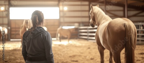 Female instructor teaches horse education and training at indoor equine farm.