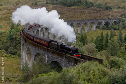 Steam train crosses the Glenfinnan viaduct in the Scottish Highlands. Famous landmark in Scotland. 