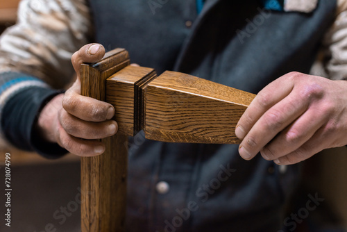 The carpenter glues the details of the cabinet leg