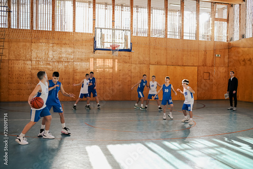 Junior basketball team practicing game on training with their coach at court.