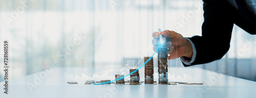 Coin stack with digital graphic indicator symbolizing business investment and economic growth. Businessman doing financial planning to achieve financial goal and contribute to profit. Shrewd