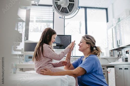 Supportive doctor high five with children patient in emergency room. Concept of emotional support and friendliness for young kid patient.