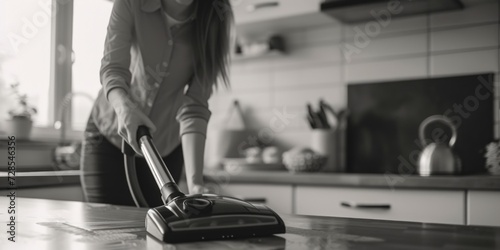 A woman using a vacuum to clean a kitchen counter. Perfect for household cleaning or domestic chores illustrations