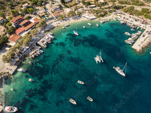  Port on a Greek island with blue turquoise water with many boats and yachts on the water in Greece, Zakynthos. Aerial drone photo of Agios Nikolaos - a small port on the island of Zante.