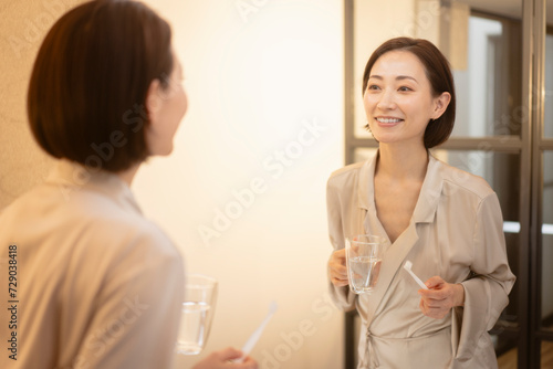 歯磨きをしながら鏡で歯の白さを見ている女性