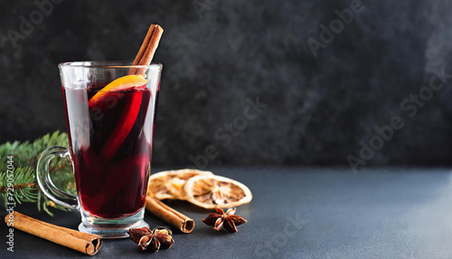 Mulled red wine with cinnamon, orange and spices with fir branches on the background