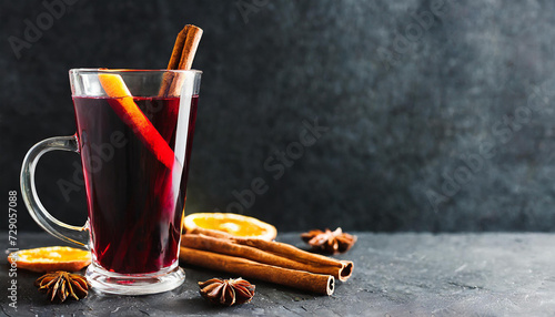 Mulled red wine with cinnamon, orange and spices on dark background