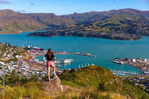 pretty hiker girl enjoying the panorama of lyttelton after finishing the hike on the bridle path from christchurch to lyttelton; beautiful view from gondola summit station, canterbury, new zealand 