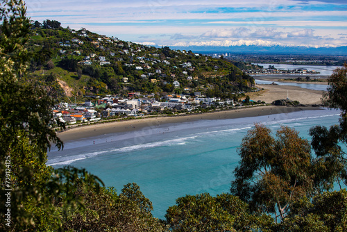 panorama of famous sumner beach in christchurch, canterbury, new zealand; beautiful beach with christchurch city and snow covered mountains in the background