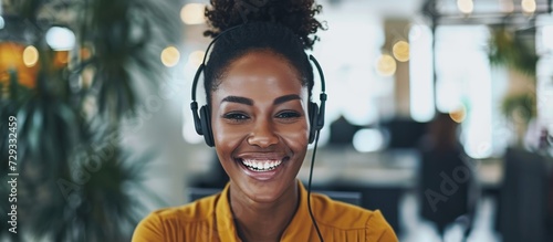 A Black call centre agent, young and laughing while on a call with a headset.