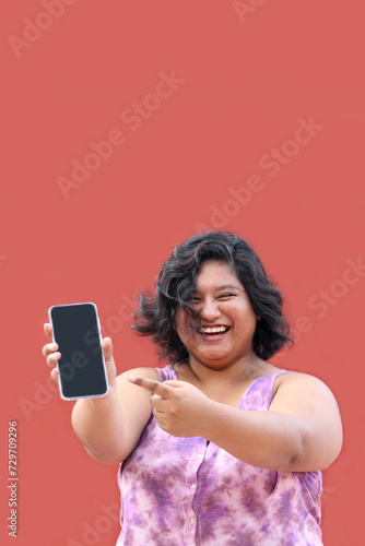 Young overweight brunette Latin woman of 20 years old shows the screen of her cell phone very happy about promotions and discounts