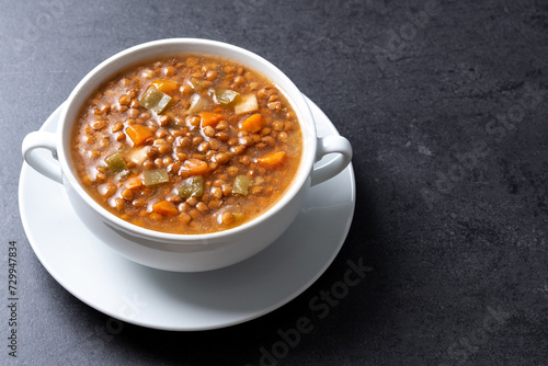 Lentil soup with vegetables in bowl on black background. Copy space