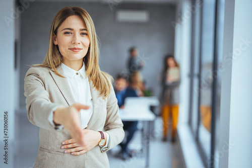 Welcome! Portrait of friendly hospitable cheerful woman giving hand to handshake, hostess greeting guest. Happy office employee giving hand for shaking