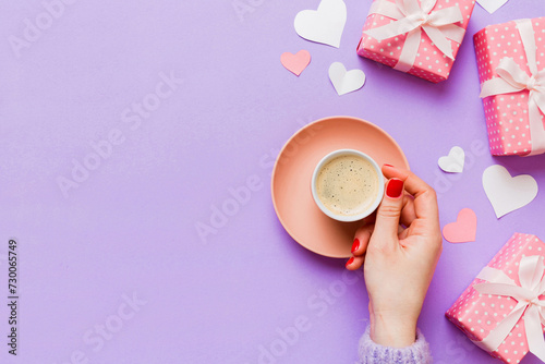 Flat lay of heart shaped cup of black coffee in the hands of women on colored background with copy space top view. Valentine day and holiday concept