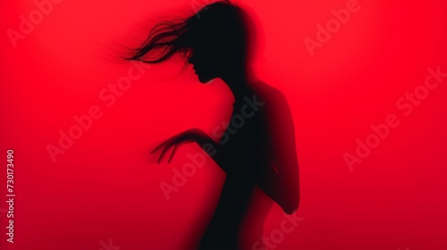 Female blurred silhouette on a red background. Elegant outline of a woman in motion out of focus