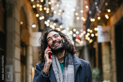 Man smiling while talking on the phone outdoors.