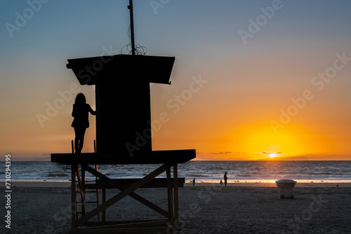 Silhouette of a girl standing on a lifeguard tower at sunset in Los Angeles