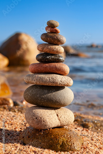 Flat stones stacked at the edge of a beach, swathed by the water waves. Zen like stones. Zen stones stacked in water. Stones stacked on a beach.