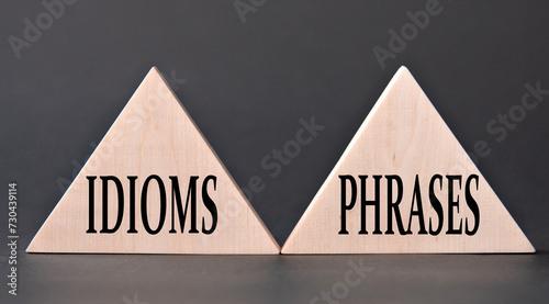 IDIOMS and PHRASES - words on wooden triangles on dark background