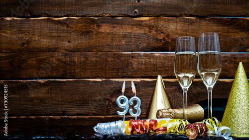 Solemn background for the anniversary with the number 93. Happy birthday background on brown wooden background with champagne bottle and champagne glasses. Beautiful holiday decorations copy space.