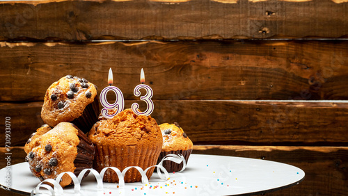 Pies with a number 93 of candles burning for the anniversary. Copy space background happy birthday on wooden background. Card or postcard festive rustic brown.