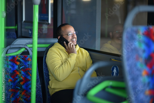 a lustful dark-skinned young man is sitting in the bus and talking on the phone