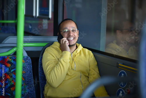 a lustful dark-skinned young man is sitting in the bus and talking on the phone