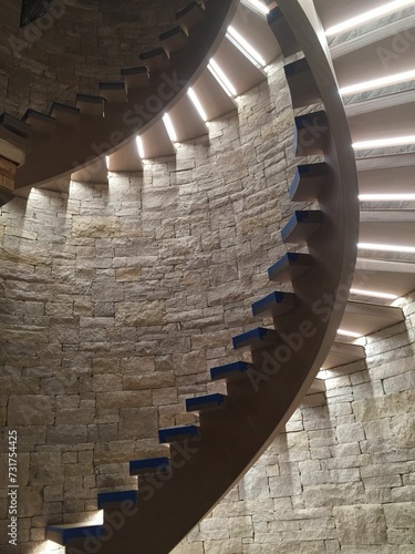 Interior shot of a stone wall featuring a staircase with illuminated spiral steps